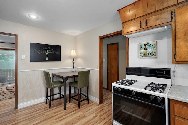 940 Carl Allen St, Mount Vernon, MO 65712 - kitchen with gas stove, brown cabinetry, light wood finished floors, light countertops, and wainscoting