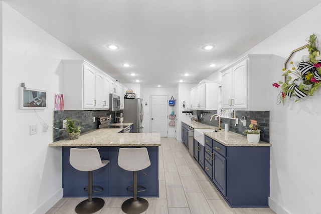 604 N Cascades Dr, Nixa, MO 65714 - kitchen with appliances with stainless steel finishes, a peninsula, decorative backsplash, a sink, and light stone counters
