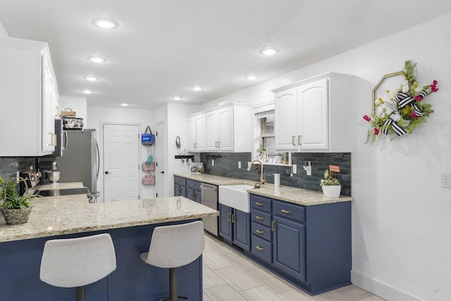 604 N Cascades Dr, Nixa, MO 65714 - kitchen featuring a sink, appliances with stainless steel finishes, decorative backsplash, white cabinets, and a peninsula