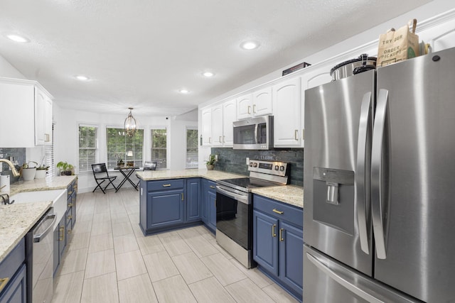 604 N Cascades Dr, Nixa, MO 65714 - kitchen with appliances with stainless steel finishes, white cabinetry, decorative backsplash, a peninsula, and blue cabinets
