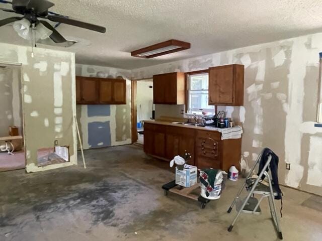 10694 Red Spring Rd, Mountain Grove, MO 65711 - kitchen with a textured ceiling, unfinished concrete floors, brown cabinetry, a ceiling fan, and light countertops