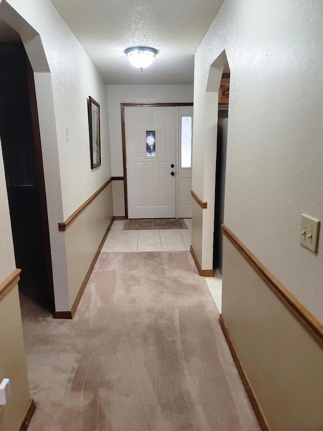 150 Sunken Forest Dr Unit 235, Forsyth, MO 65653 - hallway featuring light carpet, a textured ceiling, arched walkways, baseboards, and a textured wall