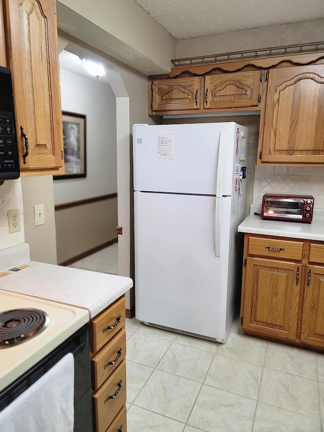 150 Sunken Forest Dr Unit 235, Forsyth, MO 65653 - kitchen featuring freestanding refrigerator, range with electric cooktop, light countertops, tasteful backsplash, and brown cabinetry