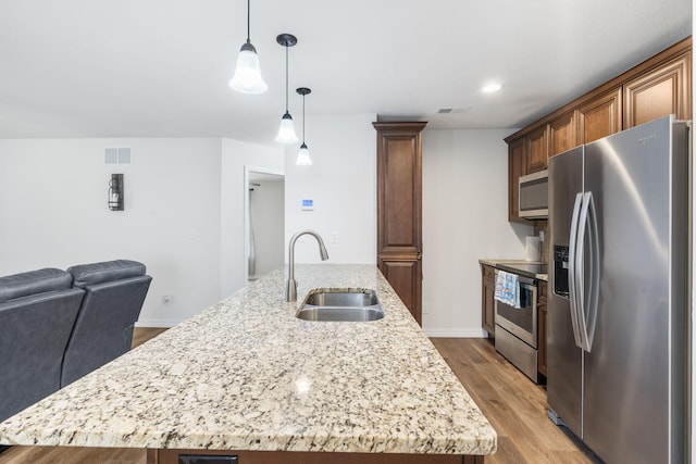 131 Lake Beach Ln, Hollister, MO 65672 - kitchen featuring appliances with stainless steel finishes, a sink, wood finished floors, open floor plan, and an island with sink