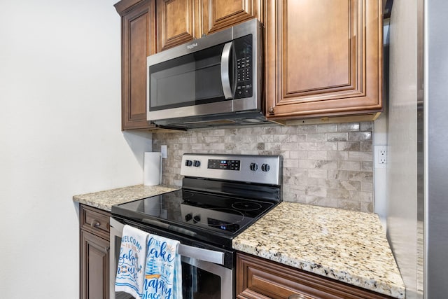131 Lake Beach Ln, Hollister, MO 65672 - kitchen featuring stainless steel appliances, backsplash, light stone countertops, and brown cabinets