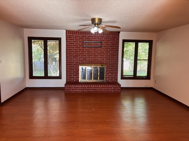 unfurnished living room with wood finished floors, a ceiling fan, a textured ceiling, healthy amount of natural light, and a fireplace