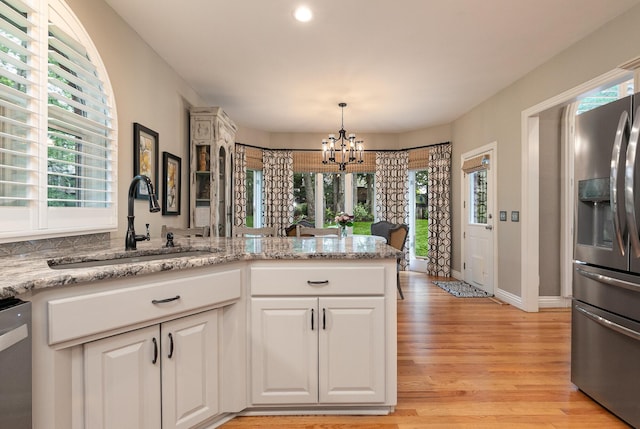 2539 S Forrest Heights Ave, Springfield, MO 65809 - kitchen featuring stainless steel appliances, a sink, a chandelier, light wood finished floors, and white cabinets
