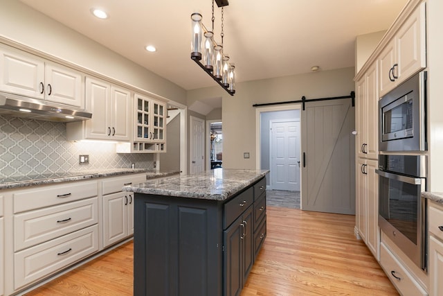 2539 S Forrest Heights Ave, Springfield, MO 65809 - kitchen featuring appliances with stainless steel finishes, under cabinet range hood, backsplash, a center island, and light wood finished floors