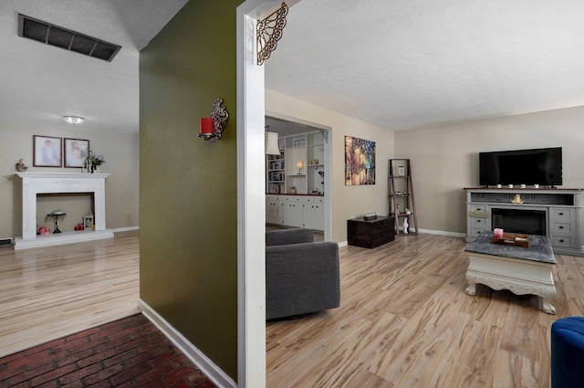 1511 E University St, Springfield, MO 65804 - living room featuring a fireplace with raised hearth, baseboards, and wood finished floors