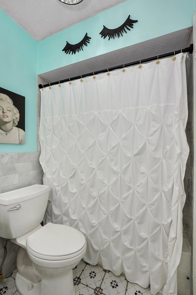 1511 E University St, Springfield, MO 65804 - bathroom featuring toilet, wainscoting, tile walls, tile patterned floors, and a shower with shower curtain