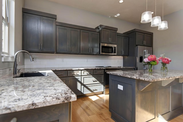 622 N Rockingham Ave, Nixa, MO 65714 - kitchen featuring stainless steel appliances, a sink, tasteful backsplash, light wood-style floors, and light stone countertops