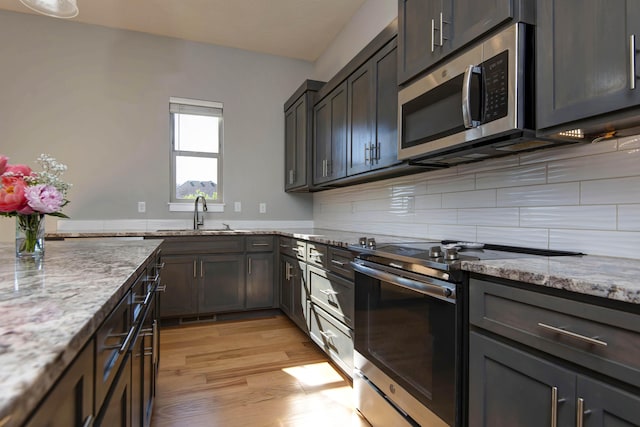 622 N Rockingham Ave, Nixa, MO 65714 - kitchen with stainless steel appliances, a sink, light wood-type flooring, light stone counters, and tasteful backsplash