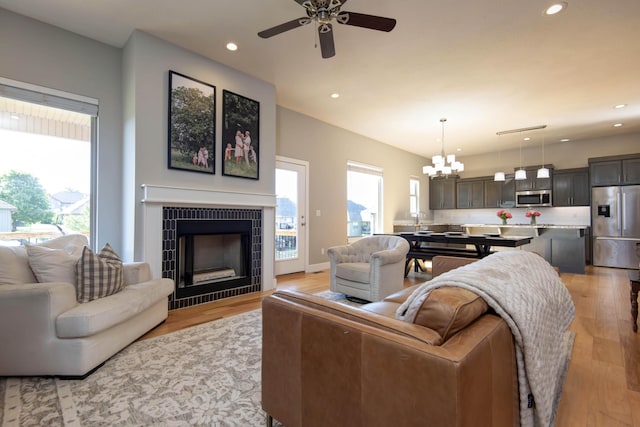 622 N Rockingham Ave, Nixa, MO 65714 - living area featuring a chandelier, a ceiling fan, a tiled fireplace, recessed lighting, and light wood finished floors
