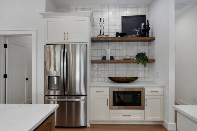 1744 E Cobblestone Dr, Ozark, MO 65721 - kitchen featuring stainless steel refrigerator with ice dispenser, built in microwave, backsplash, and white cabinetry