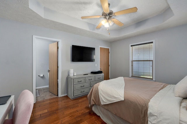 1141 N Hilton Ave, Springfield, MO 65803 - bedroom with dark wood-style flooring, a tray ceiling, a textured ceiling, baseboards, and ceiling fan