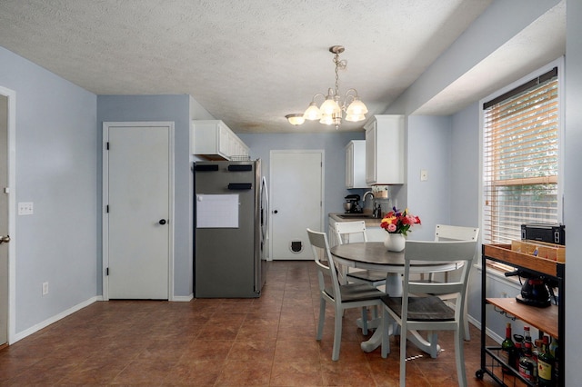 1141 N Hilton Ave, Springfield, MO 65803 - dining space with a chandelier, baseboards, and a textured ceiling