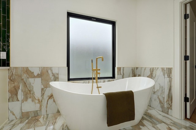 1702 E Cobblestone Dr, Ozark, MO 65721 - bathroom with marble tiled floors, tile walls, a freestanding tub, and a wainscoted wall