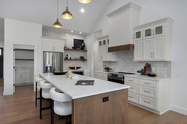1702 E Cobblestone Dr, Ozark, MO 65721 - kitchen featuring stainless steel appliances, backsplash, a kitchen bar, wood finished floors, and white cabinetry