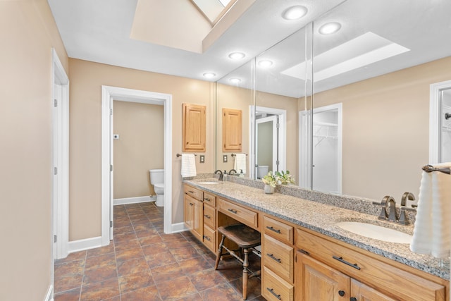 8205 Quail Ridge Ct, Nixa, MO 65714 - bathroom featuring toilet, baseboards, double vanity, a skylight, and recessed lighting