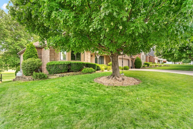 8205 Quail Ridge Ct, Nixa, MO 65714 - obstructed view of property featuring concrete driveway, a front yard, an attached garage, and brick siding