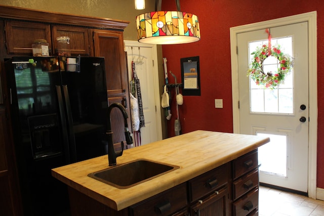 1012 E 3rd St, Monett, MO 65708 - kitchen with butcher block counters, black fridge, a sink, decorative light fixtures, and an island with sink