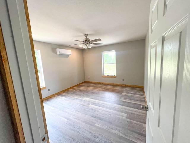 000 Reid Dr, Theodosia, MO 65761 - unfurnished bedroom with a wall mounted air conditioner, light wood-style floors, baseboards, and a ceiling fan
