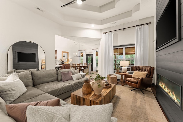 245 William Pl, Branson, MO 65616 - living room with a glass covered fireplace, a high ceiling, a raised ceiling, and a chandelier