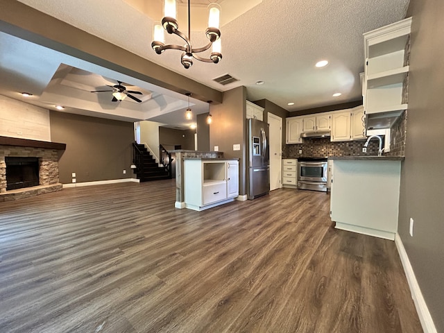 3223 W Primrose St, Springfield, MO 65807 - kitchen featuring stainless steel appliances, a raised ceiling, baseboards, open floor plan, and dark countertops