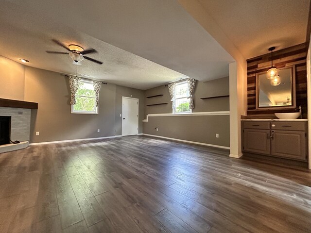 3223 W Primrose St, Springfield, MO 65807 - unfurnished living room with a ceiling fan, a textured ceiling, a fireplace with raised hearth, dark wood-type flooring, and baseboards