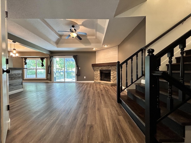 3223 W Primrose St, Springfield, MO 65807 - unfurnished living room featuring a tray ceiling, a stone fireplace, stairs, wood finished floors, and ceiling fan