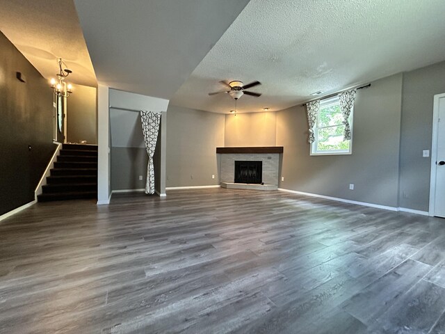 3223 W Primrose St, Springfield, MO 65807 - unfurnished living room featuring ceiling fan, a textured ceiling, stairs, wood finished floors, and a tiled fireplace