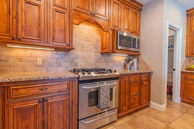 853 E Grafton Dr, Nixa, MO 65714 - kitchen with stainless steel appliances, brown cabinets, backsplash, and light stone countertops