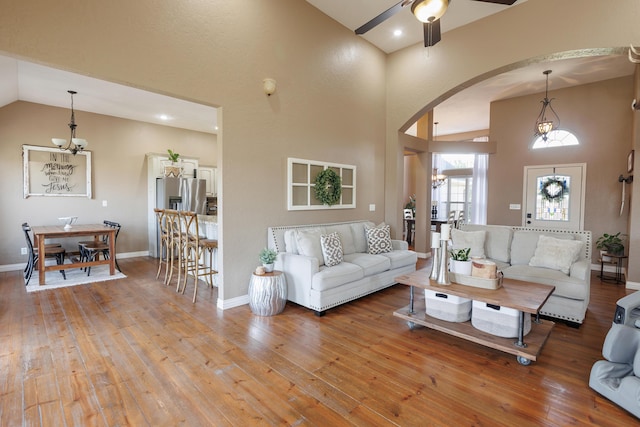 1415 Woodland Rd, Marshfield, MO 65706 - living room with arched walkways, a chandelier, hardwood / wood-style floors, high vaulted ceiling, and a ceiling fan