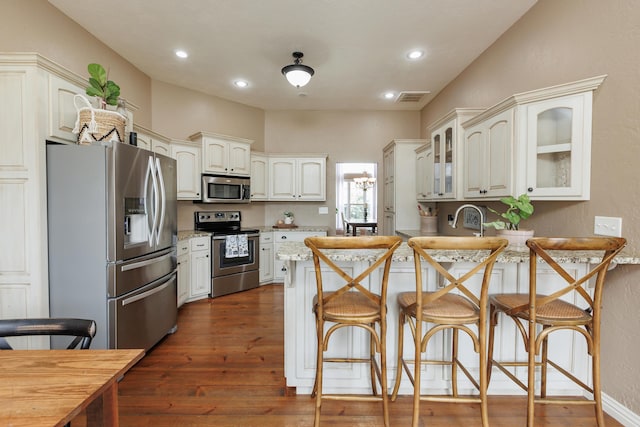 1415 Woodland Rd, Marshfield, MO 65706 - kitchen featuring stainless steel appliances, a breakfast bar, glass insert cabinets, a peninsula, and dark wood-style flooring