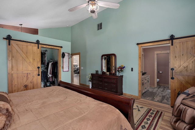 8403 Lawrence Unit 1040, La Russell, MO 64848 - bedroom with a barn door, wood finished floors, a spacious closet, connected bathroom, and high vaulted ceiling