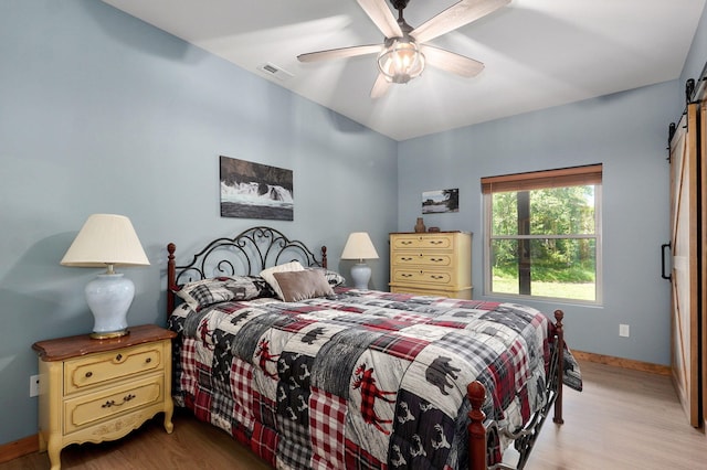 8403 Lawrence Unit 1040, La Russell, MO 64848 - bedroom with a barn door, wood finished floors, baseboards, and a ceiling fan