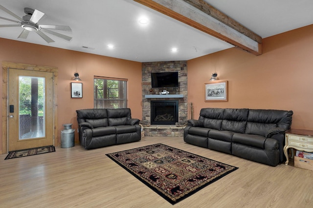 8403 Lawrence Unit 1040, La Russell, MO 64848 - living room featuring wood finished floors, plenty of natural light, a stone fireplace, beamed ceiling, and a ceiling fan