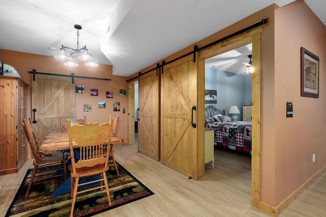 8403 Lawrence Unit 1040, La Russell, MO 64848 - dining space featuring a barn door, light wood-type flooring, baseboards, and ceiling fan