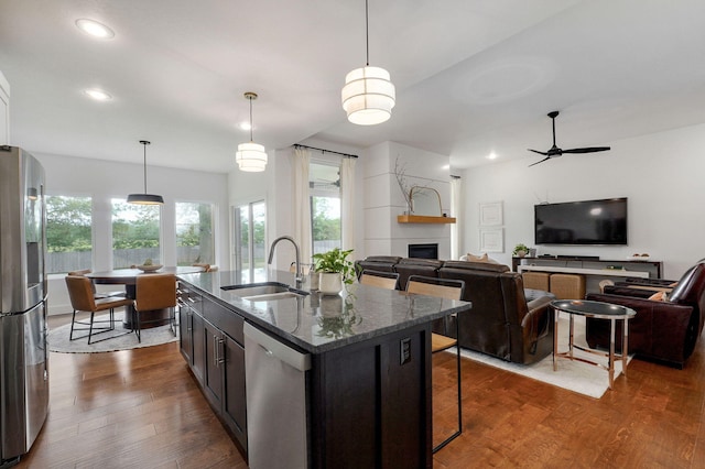 735 N Fox Hill Cir, Nixa, MO 65714 - kitchen featuring appliances with stainless steel finishes, a sink, a fireplace, dark stone counters, and a breakfast bar area