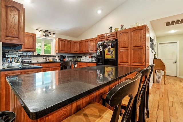 657 Plentywood Ln, Gainesville, MO 65655 - kitchen with black fridge with ice dispenser, decorative backsplash, lofted ceiling, light wood-style flooring, and brown cabinetry