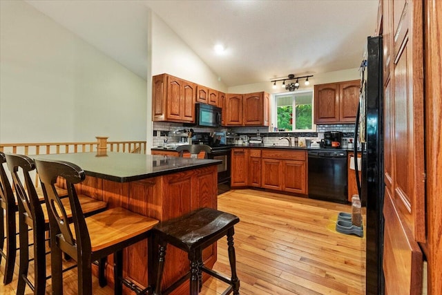 657 Plentywood Ln, Gainesville, MO 65655 - kitchen featuring black appliances, lofted ceiling, a kitchen bar, decorative backsplash, and brown cabinetry