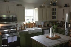 411 N Main St, Diamond, MO 64840 - kitchen with appliances with stainless steel finishes, a center island, glass insert cabinets, and light countertops