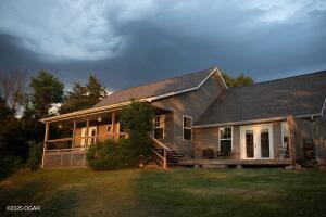 411 N Main St, Diamond, MO 64840 - back of property with a wooden deck, a lawn, french doors, and a sunroom