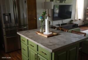 411 N Main St, Diamond, MO 64840 - kitchen with refrigerator with ice dispenser, green cabinetry, a center island, and dark wood-style floors