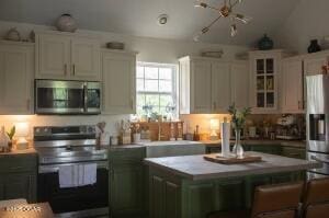 411 N Main St, Diamond, MO 64840 - kitchen with stainless steel appliances, a kitchen island, light countertops, vaulted ceiling, and glass insert cabinets