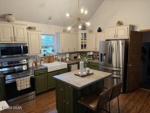 411 N Main St, Diamond, MO 64840 - kitchen featuring appliances with stainless steel finishes, dark wood-style flooring, a sink, white cabinets, and a kitchen island