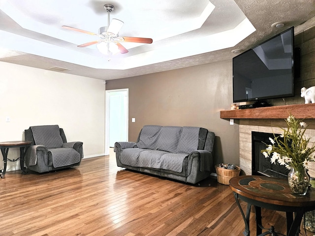 512 E Slim Wilson Blvd, Nixa, MO 65714 - living area featuring a tray ceiling, wood finished floors, a ceiling fan, and a tiled fireplace