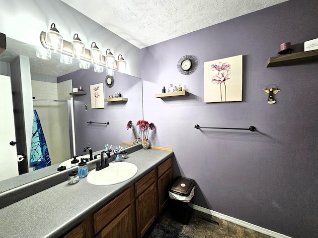 512 E Slim Wilson Blvd, Nixa, MO 65714 - bathroom with an enclosed shower, vanity, baseboards, a textured ceiling, and stone finish floors