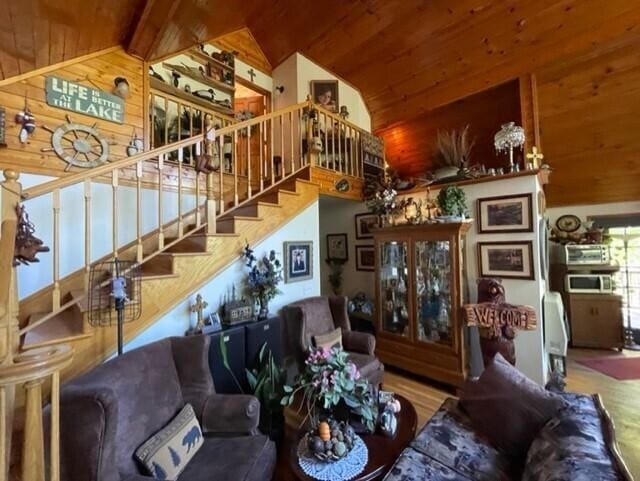 2382 Minnow Dr, Omaha, AR 72662 - living area with wooden ceiling, stairs, wood walls, wood finished floors, and high vaulted ceiling