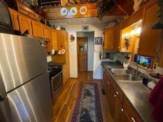 2382 Minnow Dr, Omaha, AR 72662 - kitchen featuring freestanding refrigerator, stove, brown cabinetry, a sink, and dark wood-style flooring